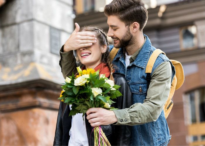 a man and woman standing next to each other with flowers in front of their face