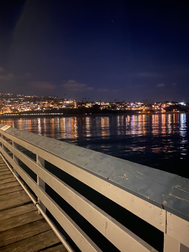 the night sky is reflected in the water and lights shine brightly on the city skyline