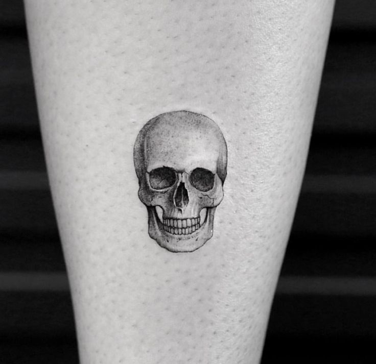 a black and white photo of a skull tattoo on the left calf's leg