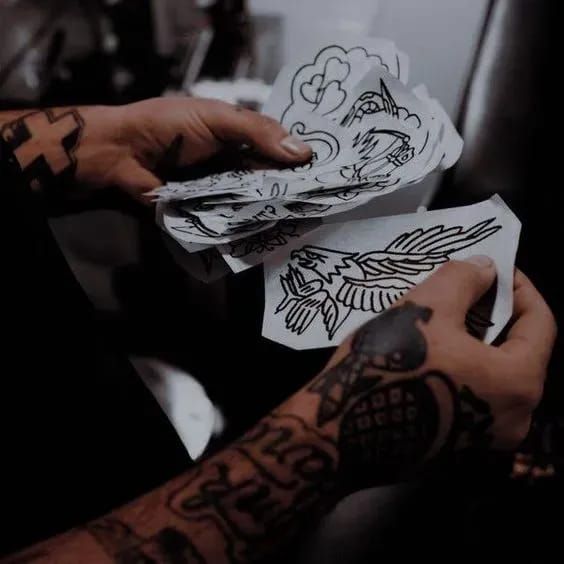 a person with tattoos on their arms holding some paper