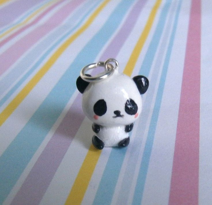 a small panda bear keychain sitting on top of a striped table cloth,