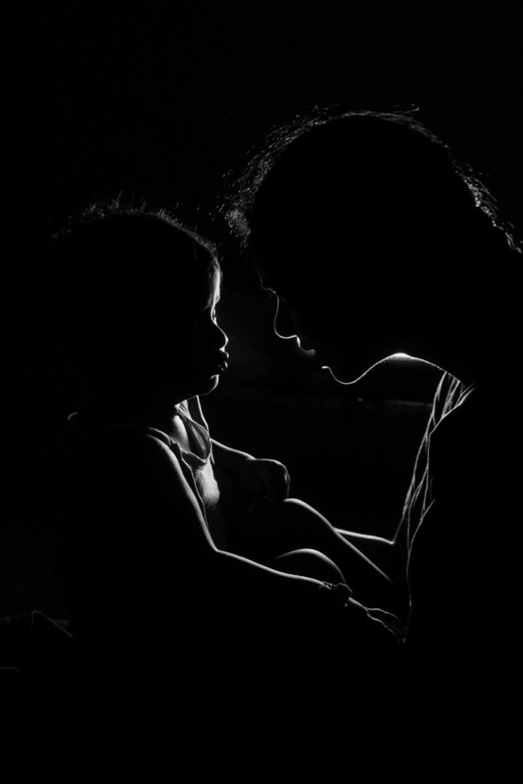 two people are sitting in the dark with their arms around each other