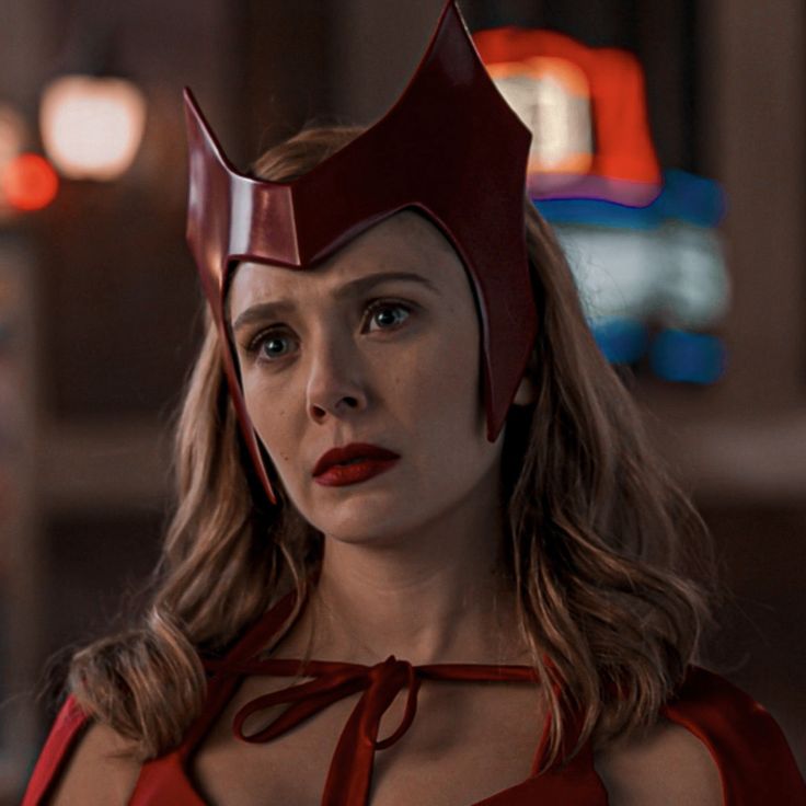 a woman in a red dress wearing a helmet with horns on her head and eyes closed