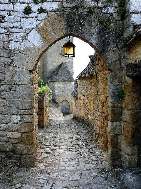 an old stone street with cobblestones and a lantern hanging from the wall above it