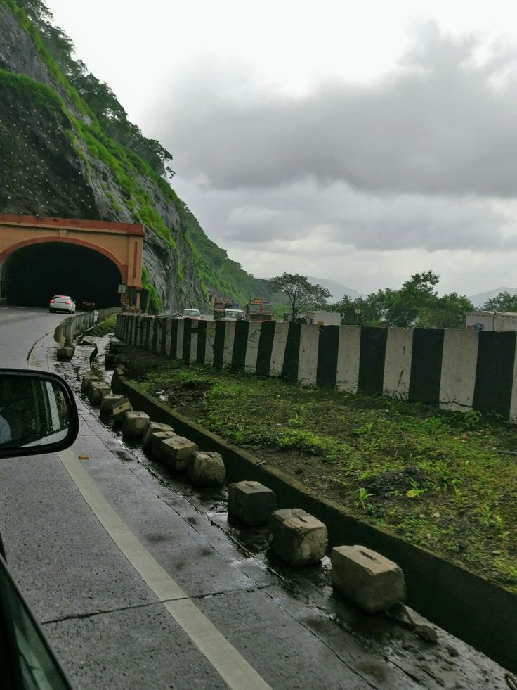 the road is wet from rain coming down and there are rocks on the side of the road