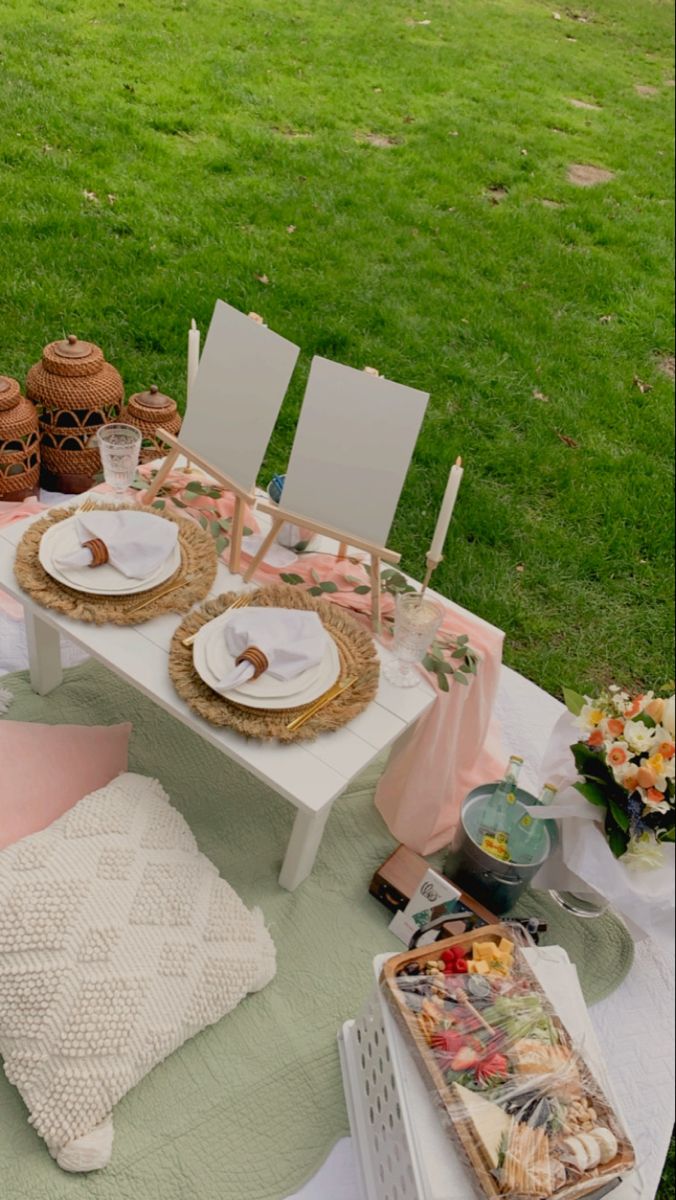 a table set up with plates and food on it in the middle of a field