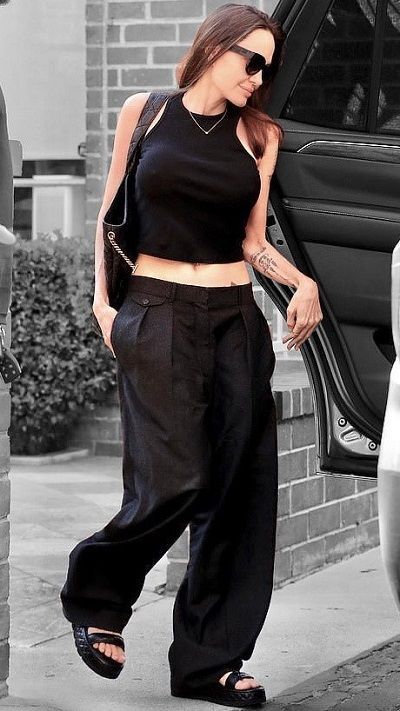 a woman in black pants and crop top stepping out of a car