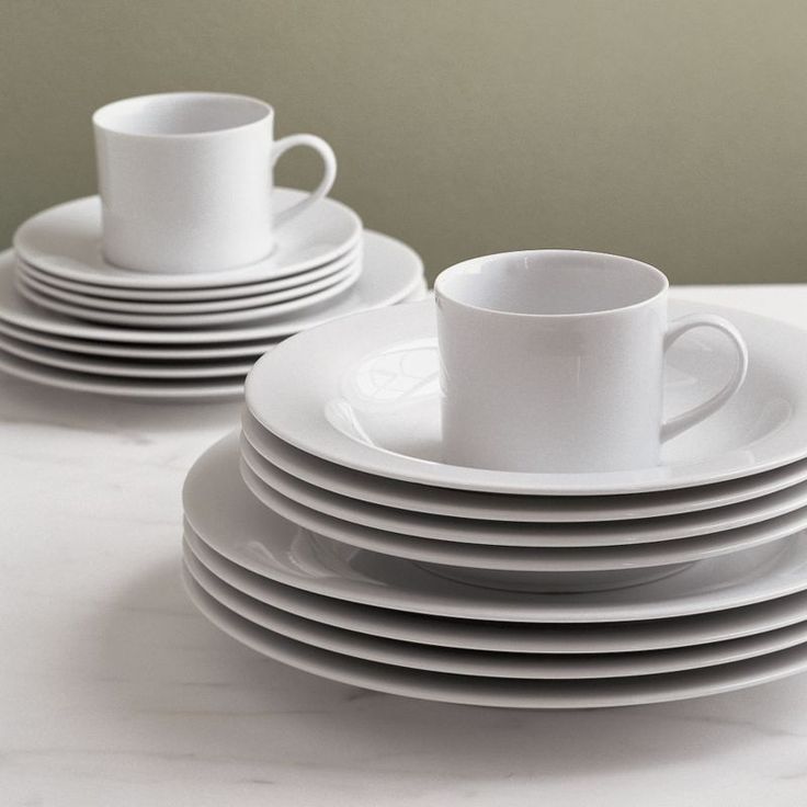 a stack of white cups and saucers sitting on top of a table next to each other