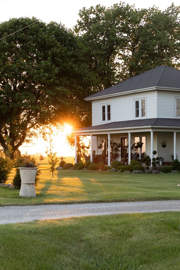 a large white house sitting on top of a lush green field