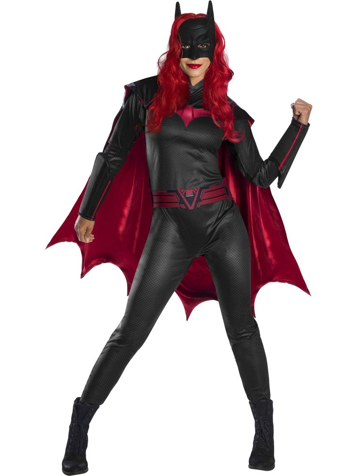 a woman dressed as batgirl standing with her arms in the air and wearing a red cape