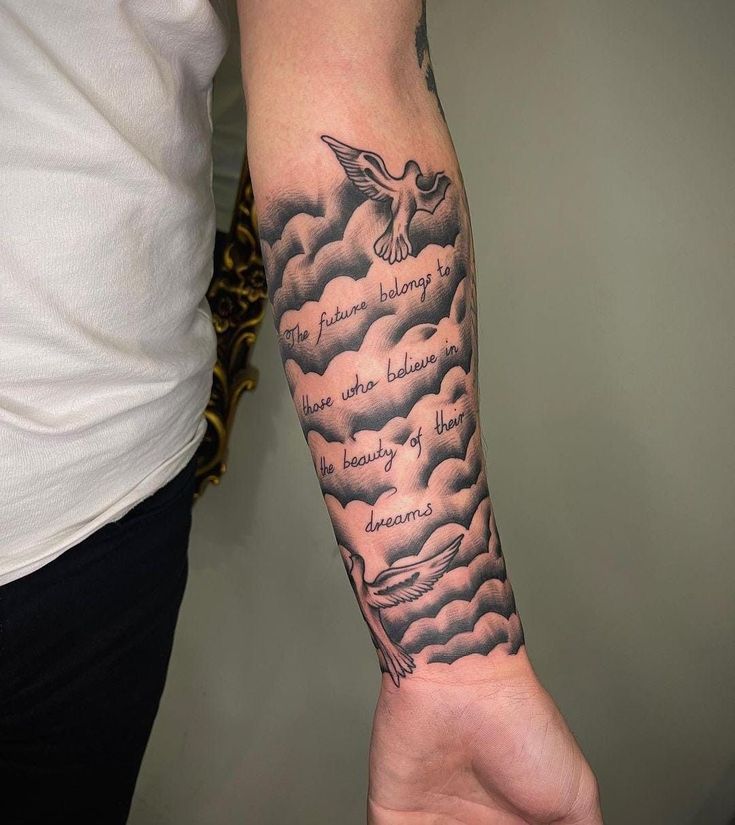 a person with a black and white tattoo on their arm that has clouds in it