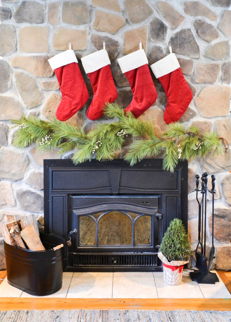 christmas stockings hanging over a fireplace with potted plants on the mantle next to it