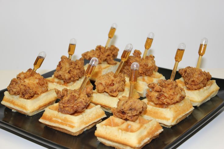 some fried chicken and waffles are on a black plate with toothpicks