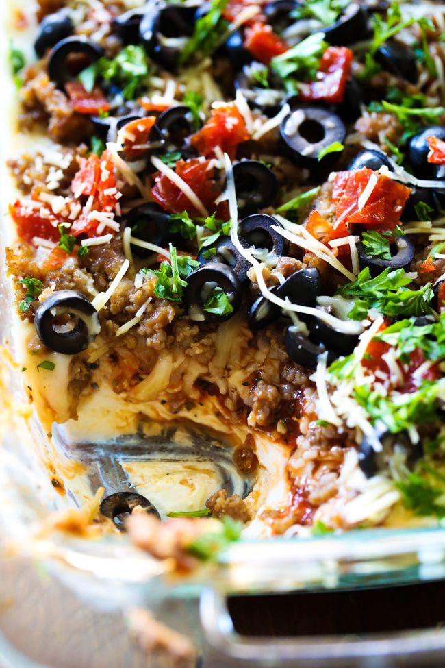 an enchilada casserole with olives, tomatoes and parmesan cheese