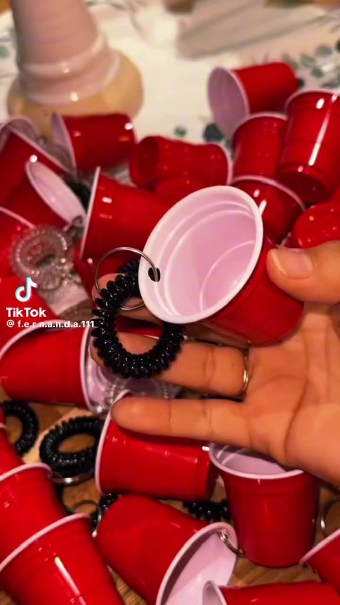 a hand holding a red cup with black beads around it and several other cups in the background