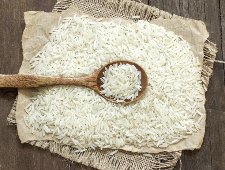 a wooden spoon sitting on top of a piece of paper next to a pile of rice