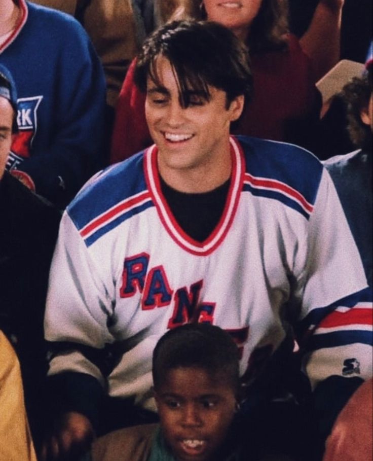 a man sitting in front of a group of people wearing jackets and smiling at the camera