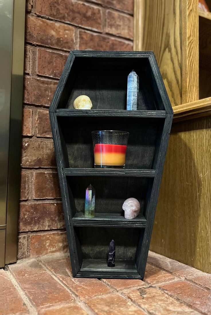 a shelf with candles, rocks and other items on it in front of a brick wall