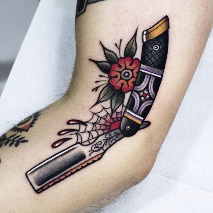 a tattoo with a knife and flowers on it