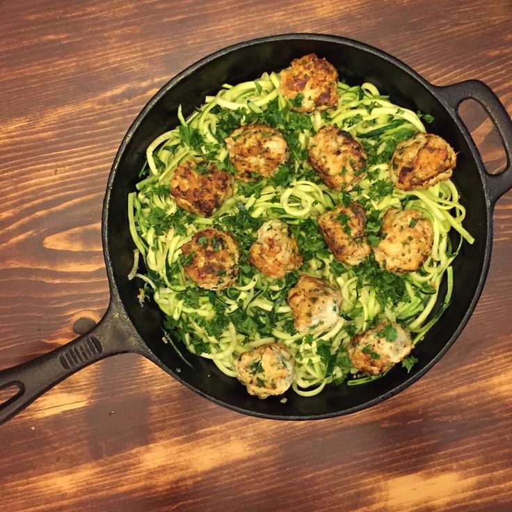 a pan filled with pasta and meatballs on top of a wooden table