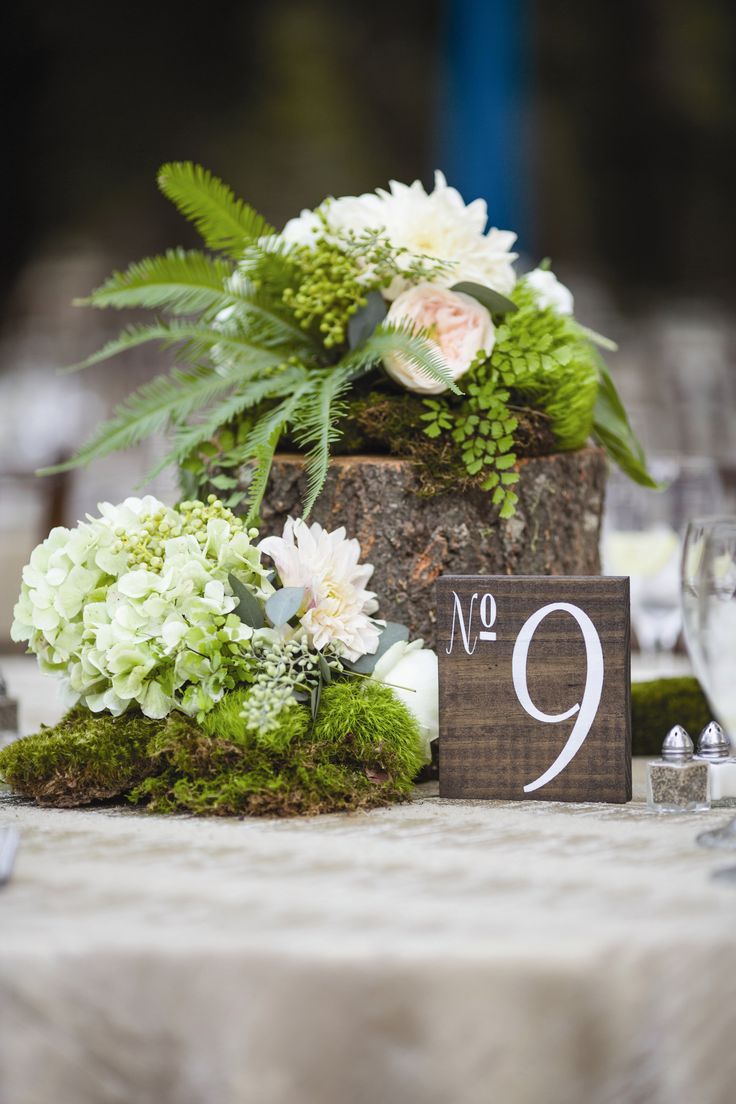 flowers and greenery are arranged on the table number 9, which sits next to a wooden block