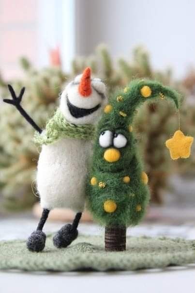 two small christmas trees on a table with one being dressed as a snowman and the other is holding a star