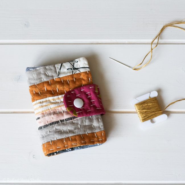 an orange, white and pink cell phone case next to a spool of thread