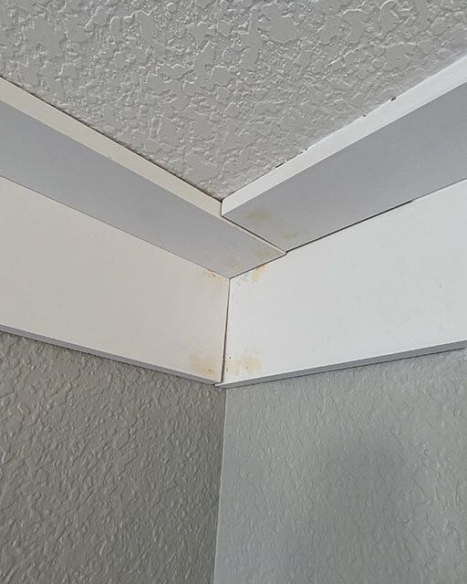 the corner of a room that has been painted white and is missing some paint on it