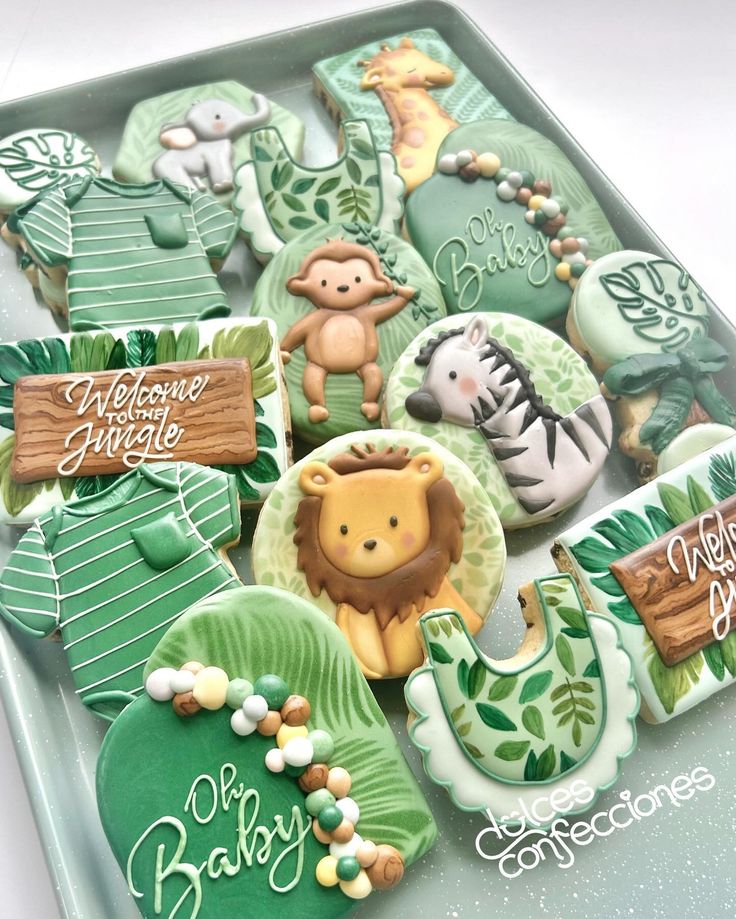 decorated cookies in the shape of animals and jungles on a tray with name tags