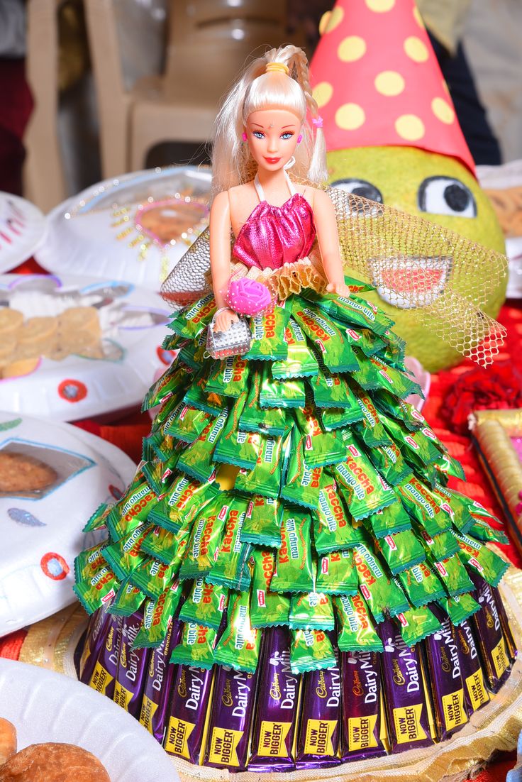 a barbie doll dressed up in a dress made out of candy bar wrappers sitting on top of a table