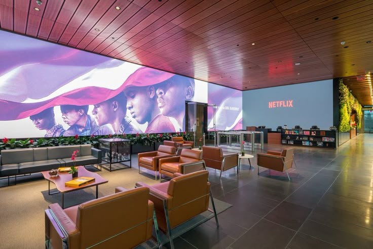 an empty lobby with couches and chairs in front of a large poster on the wall