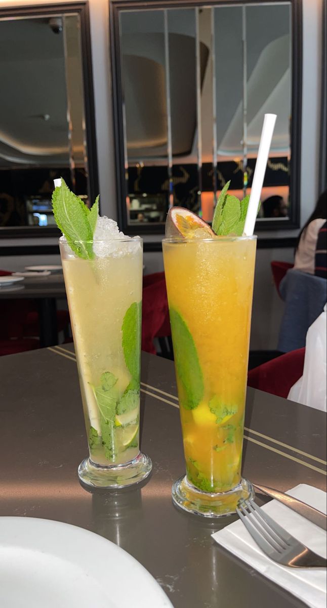 two glasses filled with drinks sitting on top of a table