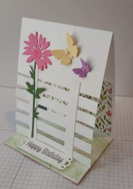 a birthday card with flowers and butterflies on the front, sitting on top of a piece of paper