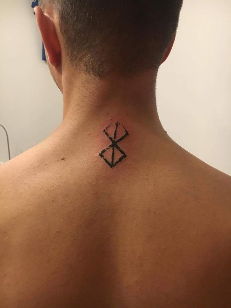 the back of a man's neck with a cross and arrow tattoo on it