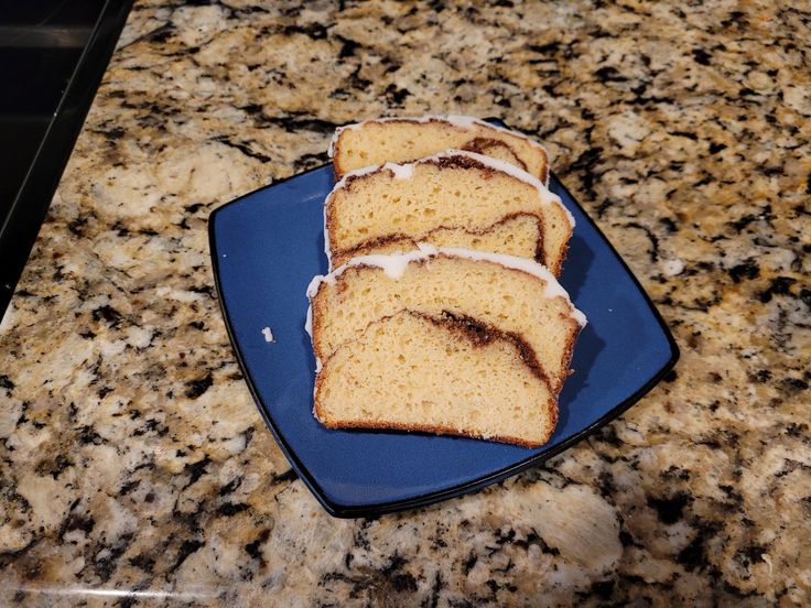 slices of cake on a blue plate sitting on a granite counter top with white icing