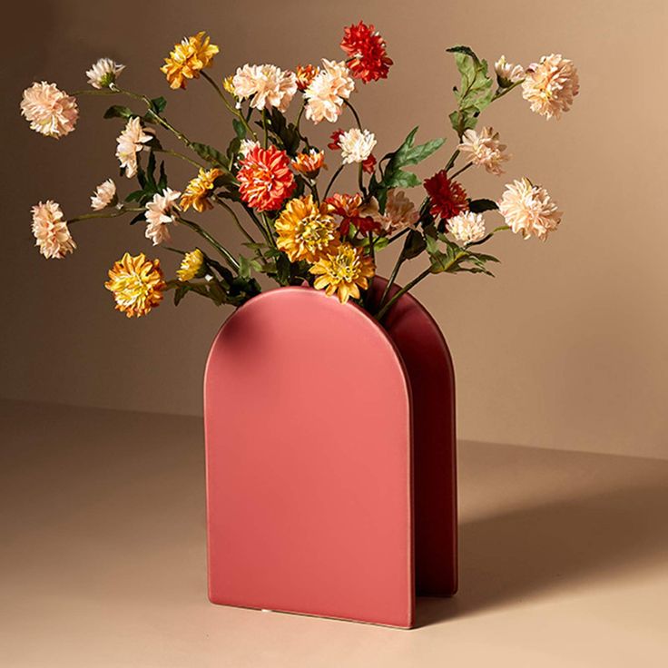 a vase with flowers in it sitting on a table next to a brown wall,