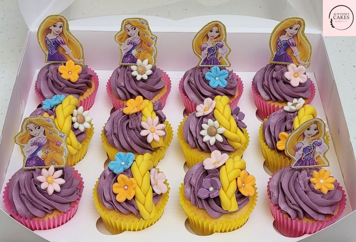 cupcakes decorated with purple frosting and yellow icing in a white box