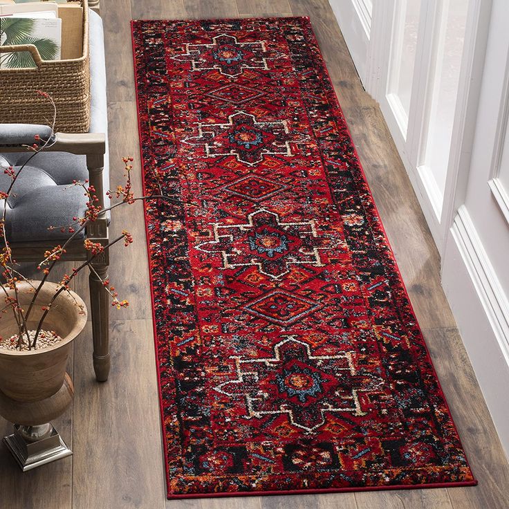 a large red rug on the floor next to a potted plant