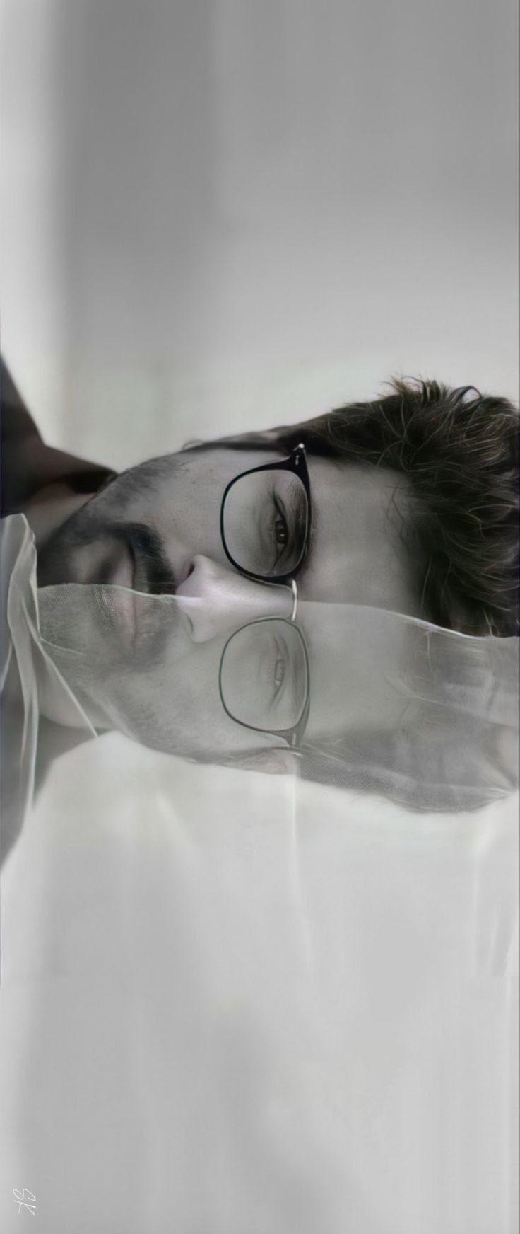 a woman with glasses laying on top of a white sheet in the middle of her body