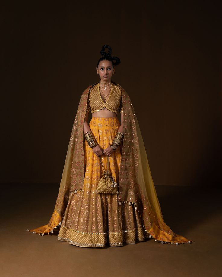 KASUNDI LEHNGA: this lehnga is made in a plush summer silk with 12 kind of flowers printed all over the base, placed in a geometric manner, and is bound with an intricate geometric border. Its hand embroidered in small mirror and sequin embroidery . The blouse is printed in small geometric pattern, then embridered with square shape sequin . Ombre Dupatta is printed and embroidered on borders and has metal coin hanging detail. Fabric : summer silk + organza mustard -olive ombre Color 15 DAYS Deli Wedding Lehenga With Mirror Work In Brocade, Diwali Brocade Traditional Wear With Mirror Work, Bollywood Style Sets With Mirror Work In Brocade, Traditional Brocade Lehenga With Mirror Work, Bollywood Brocade Sets With Mirror Work, Festive Brocade Lehenga With Mirror Work, Bollywood Style Sets With Brocade And Mirror Work, Bollywood Style Brocade Sharara With Mirror Work, Traditional Brocade Sharara With Mirror Work