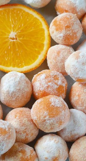 an orange and powdered sugar donuts on a table