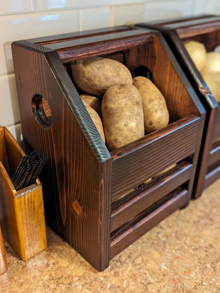 two wooden crates filled with potatoes sitting on top of a counter