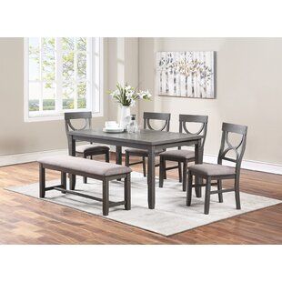 a dining room table with chairs and a bench in front of it on a rug