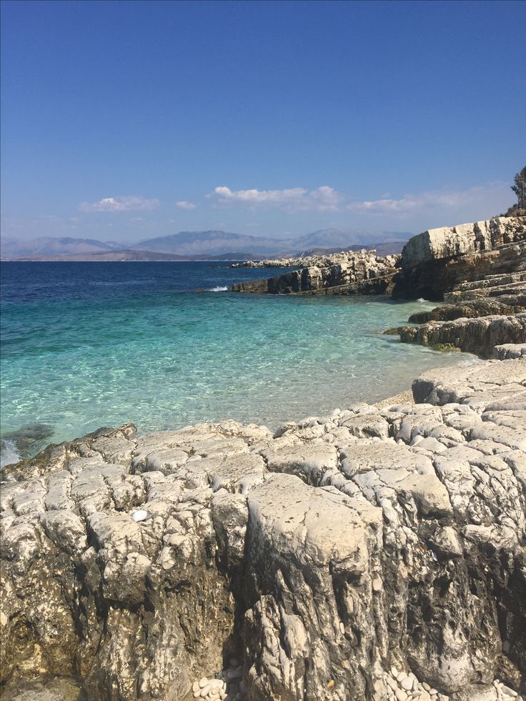 the water is crystal blue and clear with rocks on either side that are covered in white sand