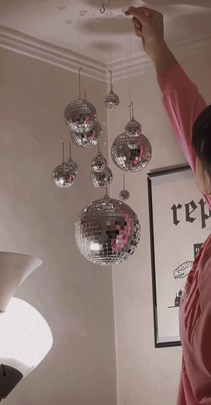 a woman standing in front of a mirror ball chandelier hanging from the ceiling