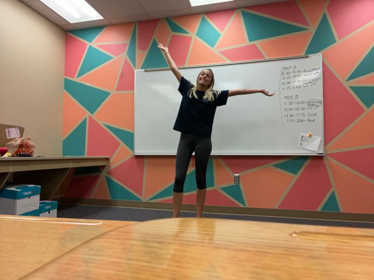 a woman standing in front of a whiteboard with writing on it and pointing to the side