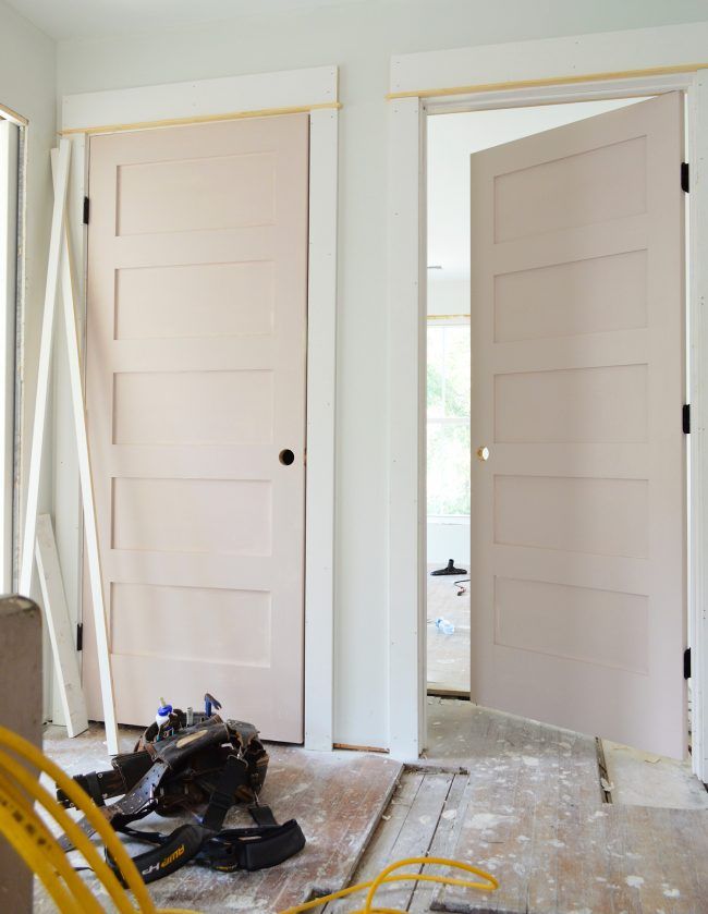 the inside of a house with two doors and tools on the floor in front of them