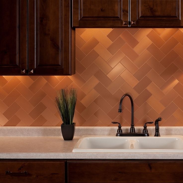 a kitchen sink with two faucets in front of a tiled backsplash