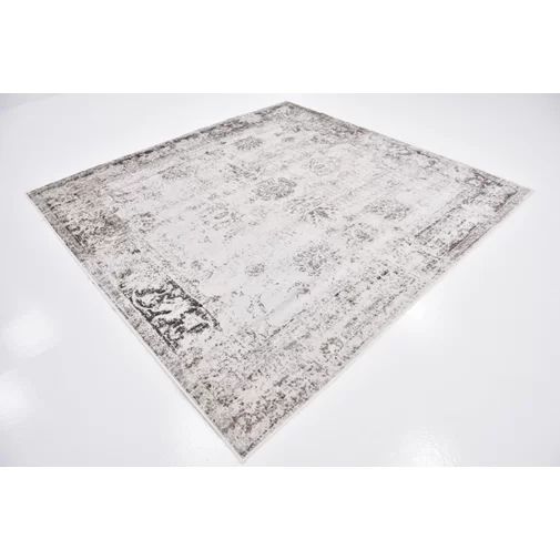 a white and gray area rug with an intricate design on the bottom, in front of a plain background