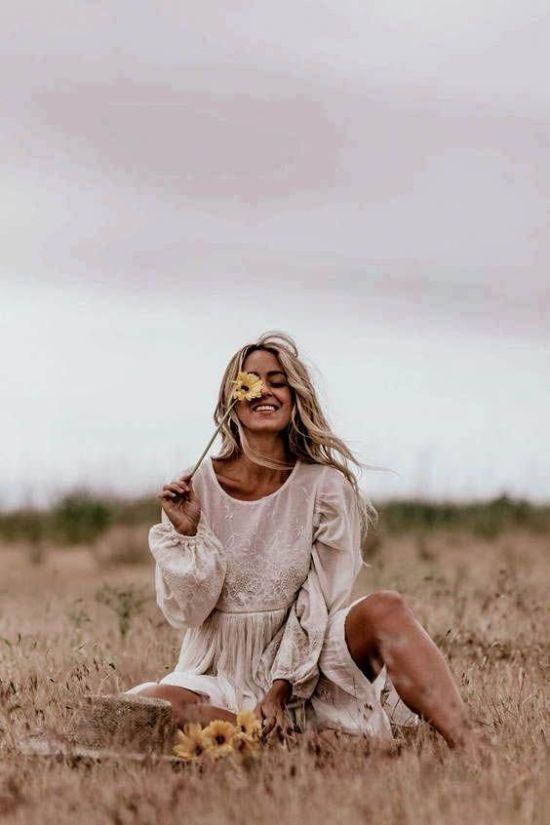 a woman sitting in a field holding a flower